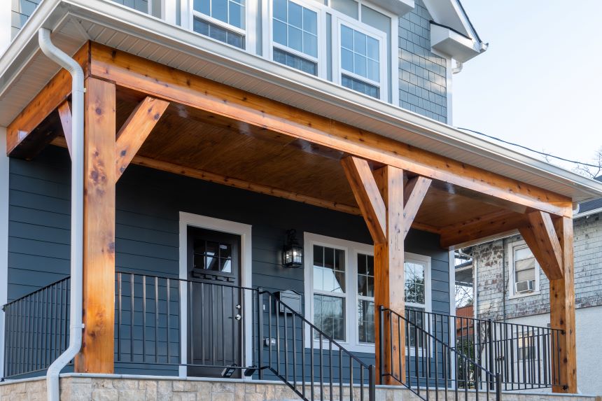 Stock image of blue residential home with covered wood porch